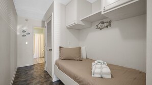 Quarto com cama, guarda-roupa e casa de banho visível através de uma porta aberta.