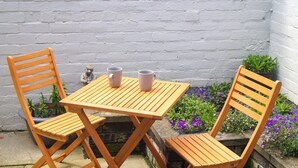 A wooden table and two chairs with a white brick wall in the background. - 2 bedroom accommodation in Amble, near Warkworth (Amble, near Warkworth)