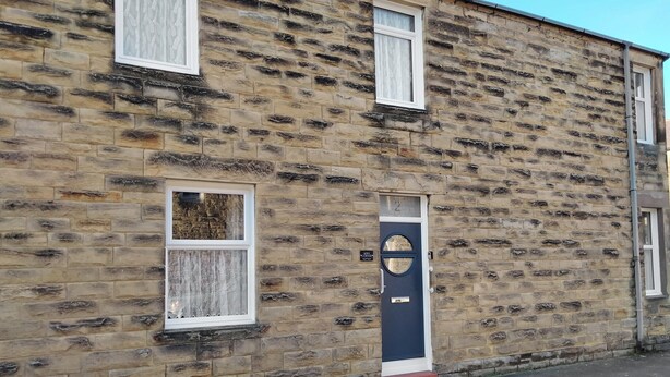 A stone building with a dark blue door and two windows with white frames. - 2 bedroom accommodation in Amble, near Warkworth (Amble, near Warkworth)