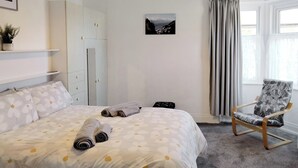 A bedroom with a bed, a chair, a wardrobe, a picture on the wall, and a window with curtains. - 2 bedroom accommodation in Amble, near Warkworth (Amble, near Warkworth)