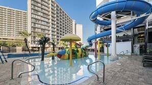 A swimming pool with a water slide and a children's play area.