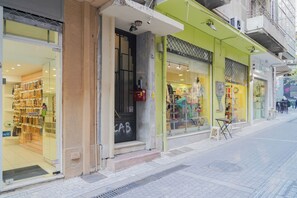 A storefront with a glass door, a visible sign, and a small outdoor seating area. - Athens Historic Centre Renovated Apartment (Athina)