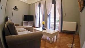 A living room with a sofa, a coffee table with a vase, a TV, and a radiator. - Athens Historic Centre Renovated Apartment (Athina)