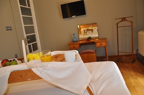 A neatly made bed with a white bedspread, a bedside table with a vase, a cup, and a plate of fruit. - Athens Historic Centre Renovated Apartment (Athina)