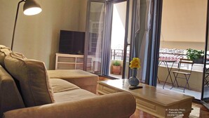 A living room with a sofa, a coffee table with a vase, a lamp, and a TV on a stand. - Athens Historic Centre Renovated Apartment (Athina)