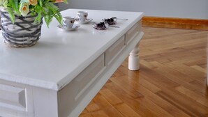 A white table with a vase of flowers, a framed painting, and a small tea set. - Athens Historic Centre Renovated Apartment (Athina)