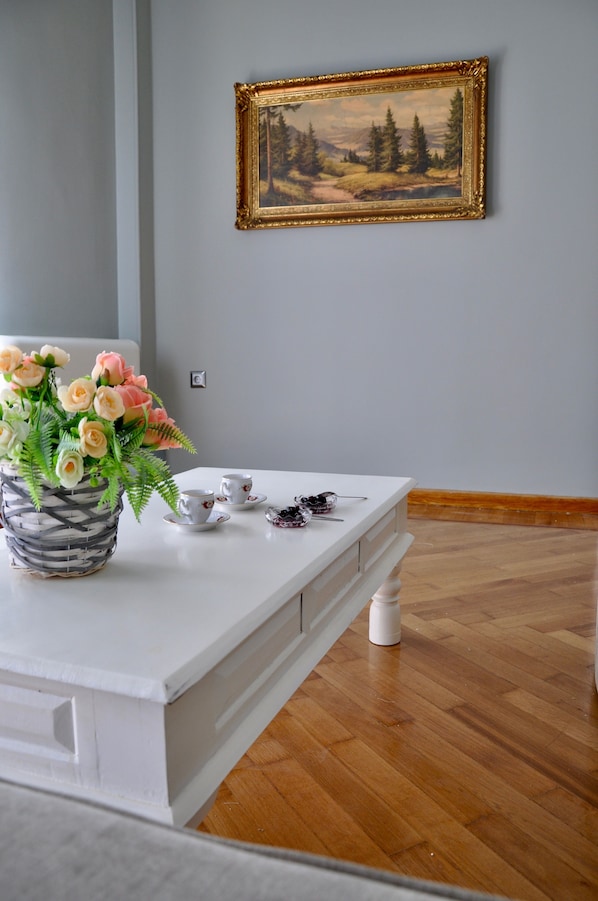 A white table with a vase of flowers, a framed painting, and a small tea set. - Athens Historic Centre Renovated Apartment (Athina)