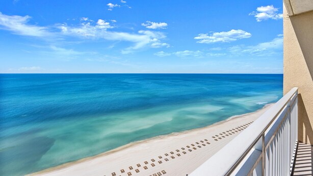 A beach view from a balcony with a railing, clear blue sky, and calm sea. - Gulf-Front 2 Bed, 2 Bath • Sleeps 8 • Amenity-Packed • Beach Chair Service for 2 (Panama City Beach)