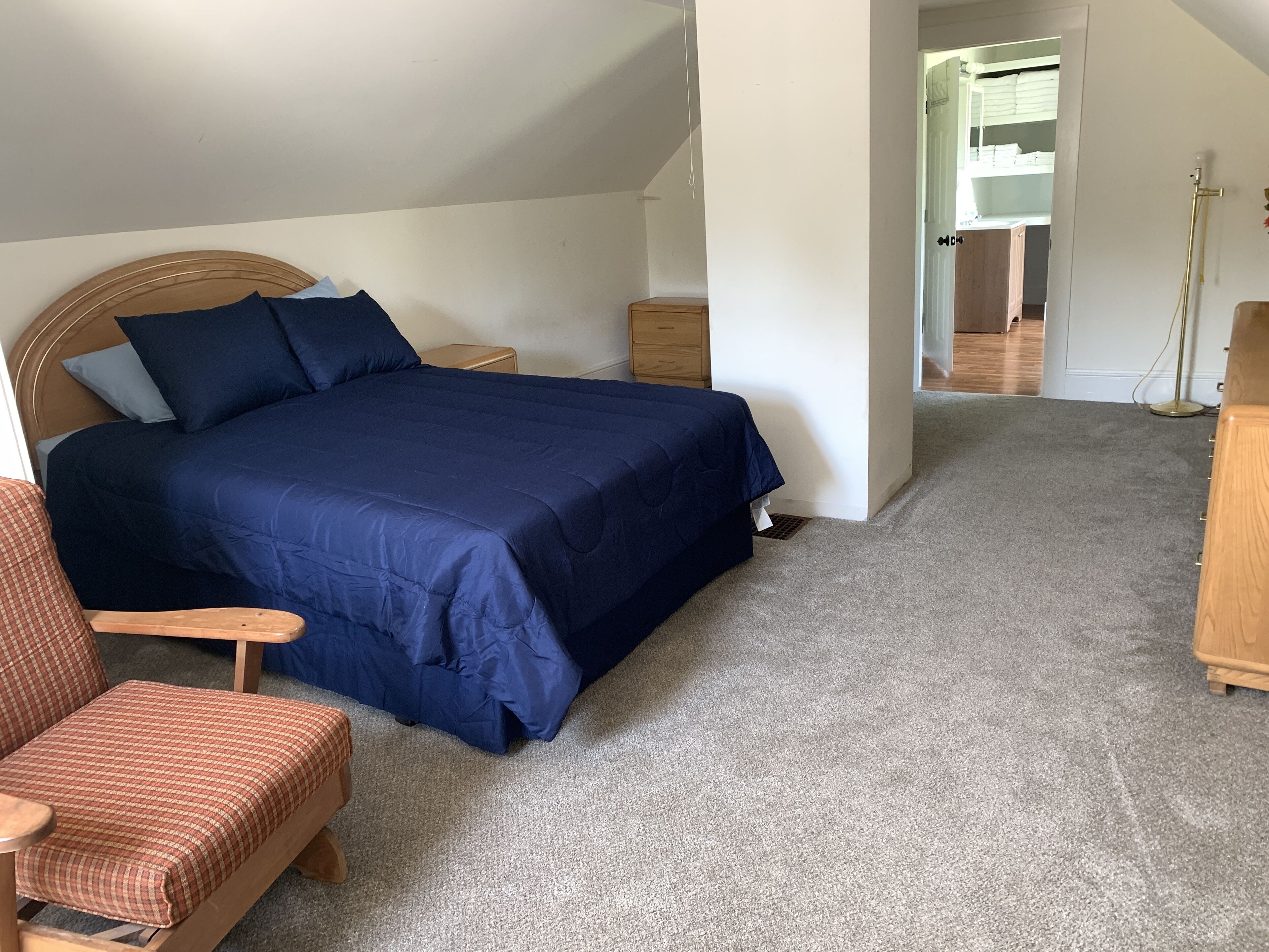 Ein Schlafzimmer mit einem Bett, einem Sessel, einem Nachttisch und einer Kommode.