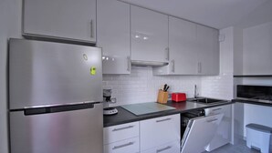 Eine moderne Küche mit Edelstahlgeräten, weißen Schränken und einer schwarzen Arbeitsplatte.