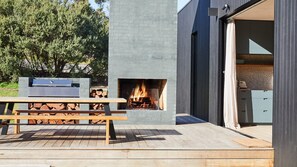 An outdoor patio with a built-in fire feature, a grill, and a wooden table.