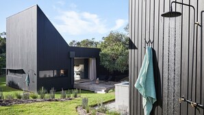 A modern outdoor bathroom with a shower and a towel hanging on a rack. - THE BACH - ST ANDREWS BEACH (St Andrews Beach)