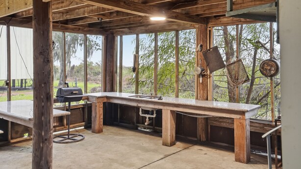 An outdoor kitchen with a long countertop, a grill, and a hanging rack. - Beautiful, Relaxing, Spacious Cottage with view of Vermillion Bay! (Cypremort Point)