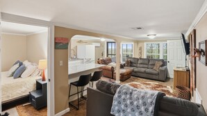 A spacious living area with a sofa, a coffee table, and a dining area with a kitchen in the background. - Beautiful, Relaxing, Spacious Cottage with view of Vermillion Bay! (Cypremort Point)