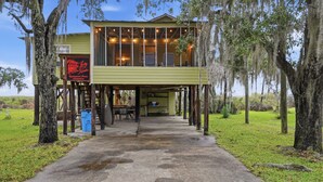 A rustic cabin with a covered porch, a dining area, and a sign indicating it is a bed and breakfast. - Beautiful, Relaxing, Spacious Cottage with view of Vermillion Bay! (Cypremort Point)