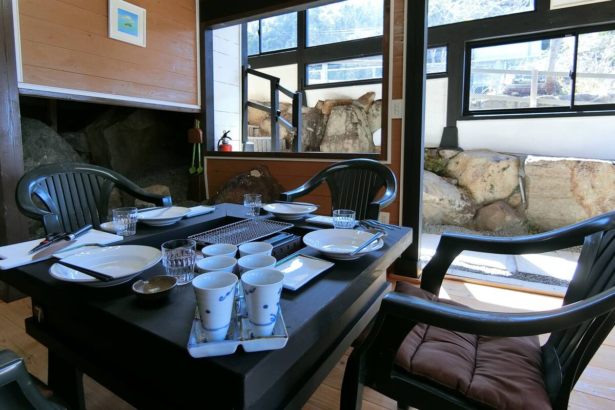 Un coin repas avec une table dressée pour quatre personnes, des chaises et un barbecue.