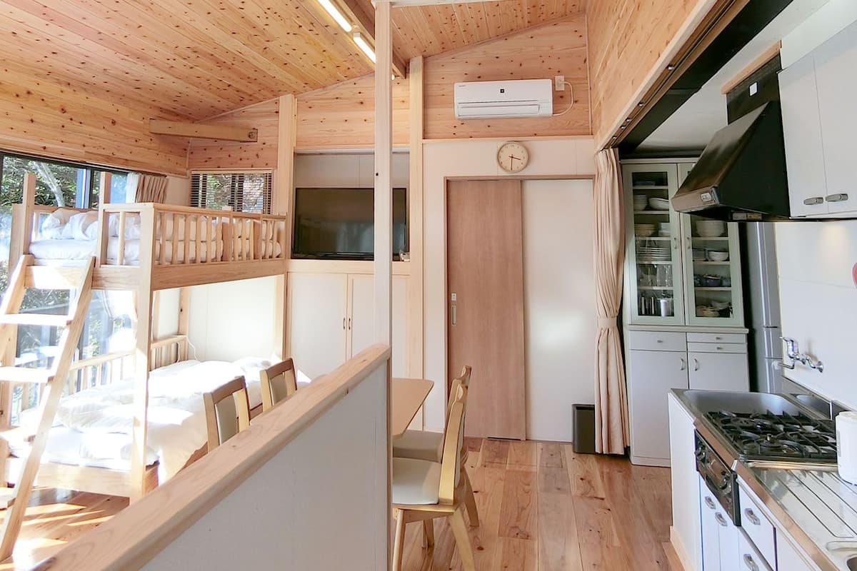Une cuisine moderne et compacte, dotée de meubles en bois, d’une cuisinière intégrée et d’un coin repas avec une table et des chaises en bois.
