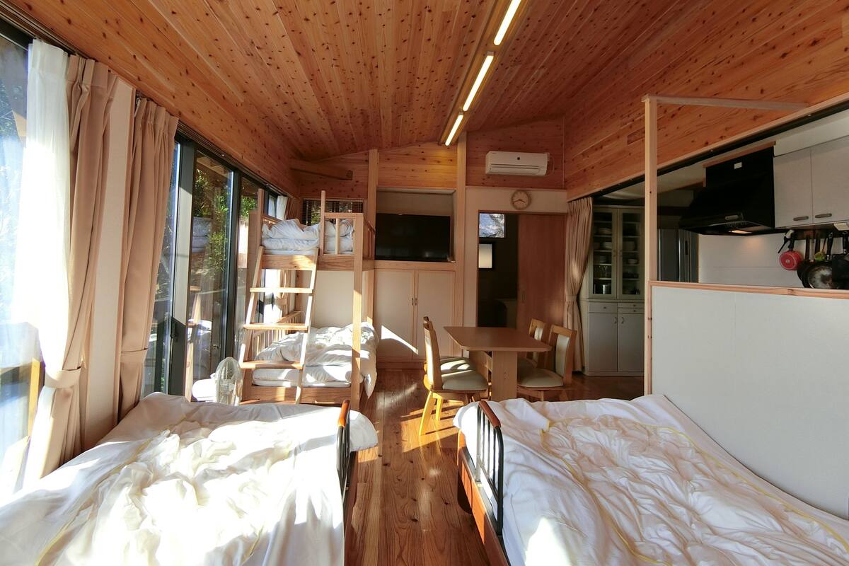 Une cabine équipée de deux lits, d’une table à manger, d’un coin cuisine et d’une grande fenêtre.