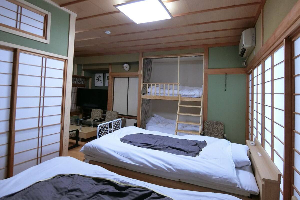 Une chambre avec des lits superposés, un bureau, une chaise, une télévision et une horloge.