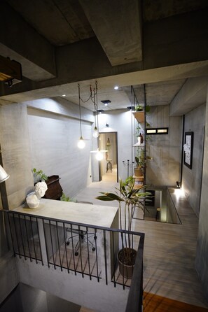 A modern interior with a concrete ceiling, a staircase, and a view into another room. - Looft (Hengchun)