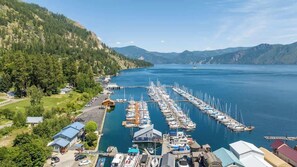 A marina with boats docked, surrounded by forested hills and a clear sky.