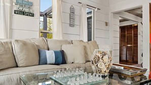 A living room with a beige sofa, a glass coffee table with chess pieces, and a decorative vase. - Lakefront Float Home with Huge Deck & Water Toys (Bayview)
