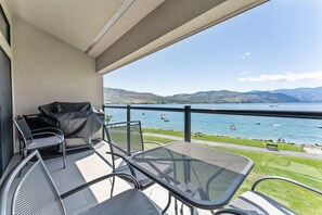 Enjoy a serene lake view from this balcony with a metal table and two chairs, perfect for taking in the surrounding mountains.
