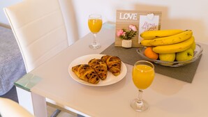 Taula amb croissants, un got de suc d'aranja, un bol de plàtans i un plat de croissants.