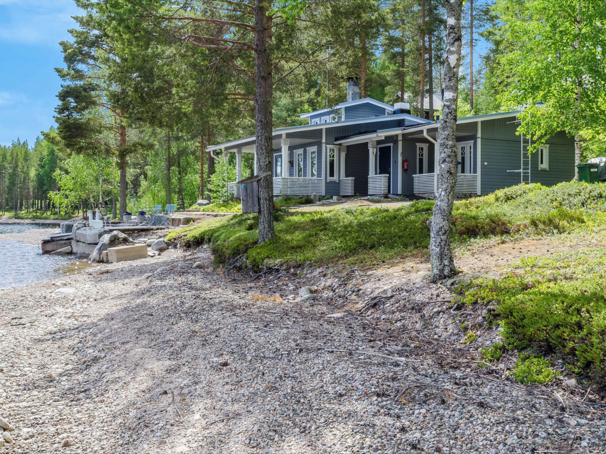Un chalet au bord du lac, doté d’un quai, et entouré d’une forêt dense.