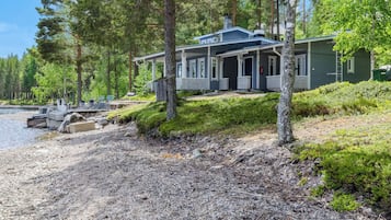 Un chalet au bord du lac, doté d’un quai, et entouré d’une forêt dense.