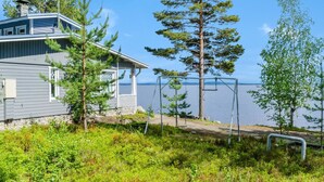Ein Haus mit einem Steg, der in einen See führt, umgeben von Grünflächen und Bäumen.