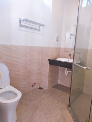 A bathroom with a toilet, sink, and glass shower enclosure. - Modern house (Nha Trang)