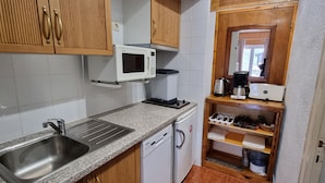 A compact kitchen with a granite countertop, stainless steel sink, white microwave, and a coffee maker. - TRES ESTRELLES CLUB 3-estudi 3 pers-Pas de la casa- 20 m piste-005986 (PAS DE LA CASA)
