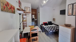 A compact living space with a dining area, a bed with patterned bedding, a TV, and artwork on the walls. - TRES ESTRELLES CLUB 3-estudi 3 pers-Pas de la casa- 20 m piste-005986 (PAS DE LA CASA)