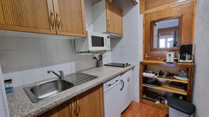 A compact kitchen with a stainless steel sink, a microwave, and wooden cabinets.