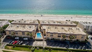 Luchtbeeld van een hotel met een zwembad, parkeerplaats en uitzicht op het strand.