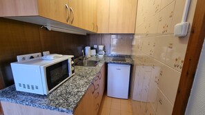 A compact kitchen with a microwave, toaster, coffee maker, and a small refrigerator.