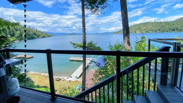 A deck with a view of a lake and forest. - Cabin With Hot Tub And Private Dock in Bottle Bay (Sagle)