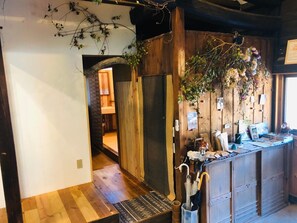 Un interior rústico con paredes de madera, un mostrador de madera con sombrillas, y un baño a la vista.