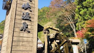A wooden sign with Japanese characters, a traditional water wheel, and a stone pathway.