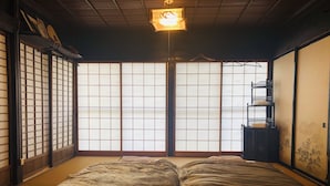 Une pièce de style japonais traditionnel, avec un sol recouvert de tatamis, des paravents shoji et un futon servant de lit.