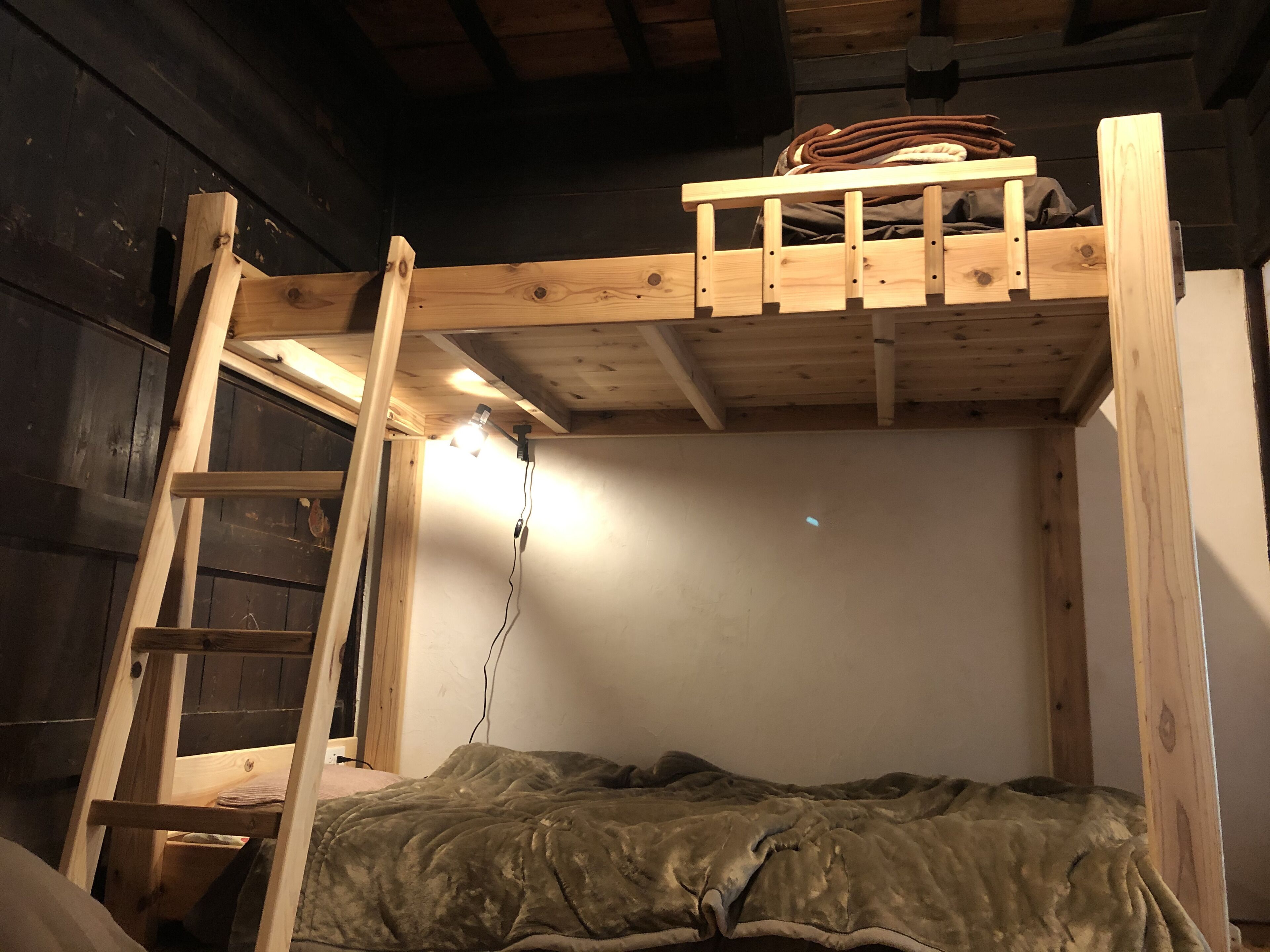 Una cama litera con escalera de madera y cabecero.