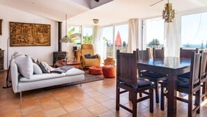 A spacious living room with a large dining table, comfortable seating, a fireplace, and a view of the outdoors.