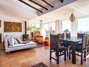 Un salon spacieux avec une grande table à manger, des sièges confortables, une cheminée et une vue sur l’extérieur.