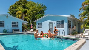 A swimming pool with clear blue water, surrounded by light blue buildings with windows and a door. - Wilton Manors, Cute Outdoor Space-New Bathroom, Pool 3 (Wilton Manors)