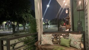 A balcony with a wooden bench, a small table, and a potted plant. - Charming New Orleans Bungalow Steps from French Quarter (New Orleans)