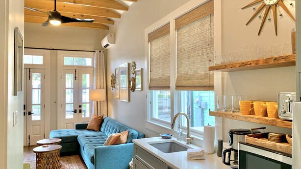 A modern kitchen with a built-in oven, a sink, and a coffee maker. There is a blue sofa and a small round table in the living area. - Charming New Orleans Bungalow Steps from French Quarter (New Orleans)