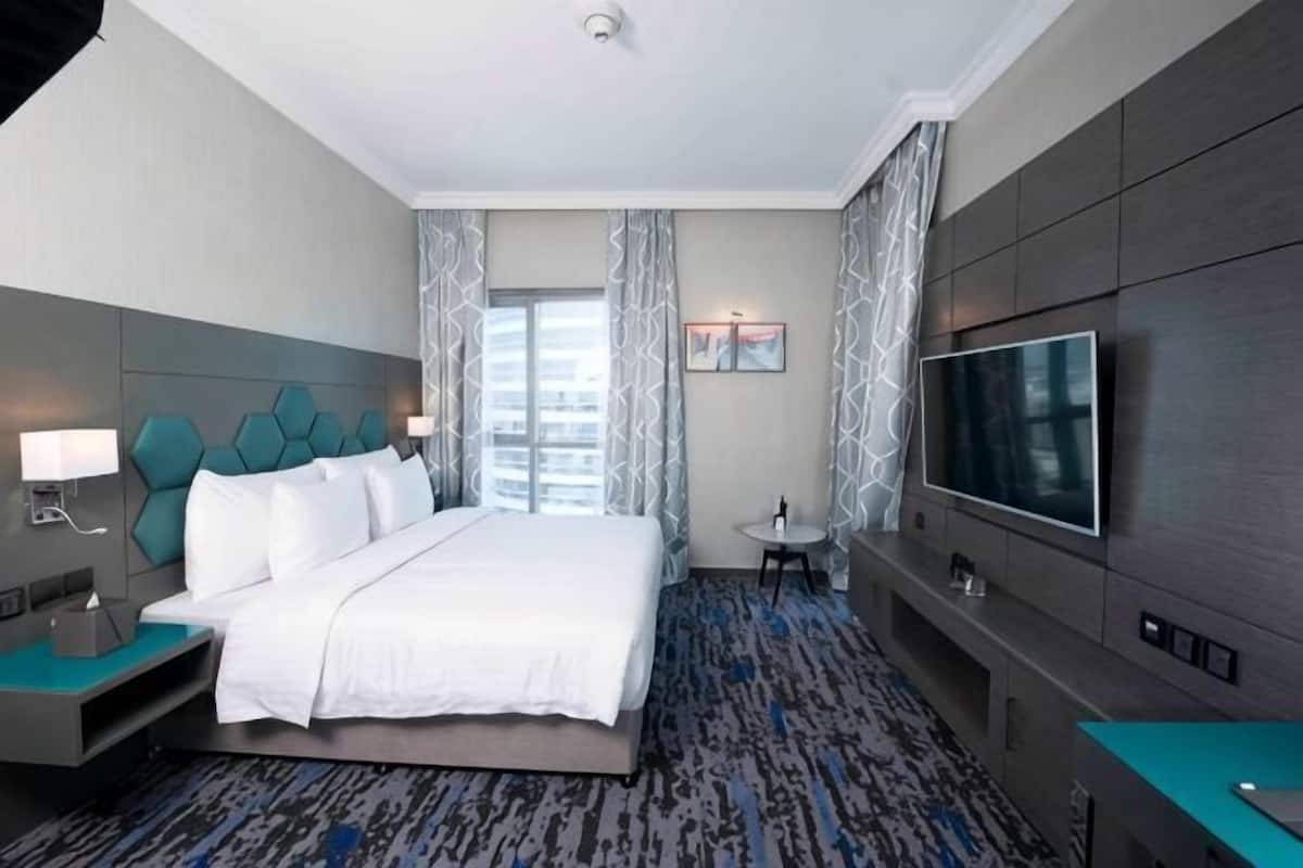 A hotel room with a bed, a TV, a desk, and a chair.