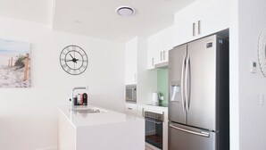 Uma cozinha moderna com geladeira de aço inoxidável, forno embutido e cafeteira no balcão.