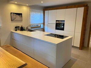 A modern kitchen with a central island, built-in appliances, and a wooden bench.